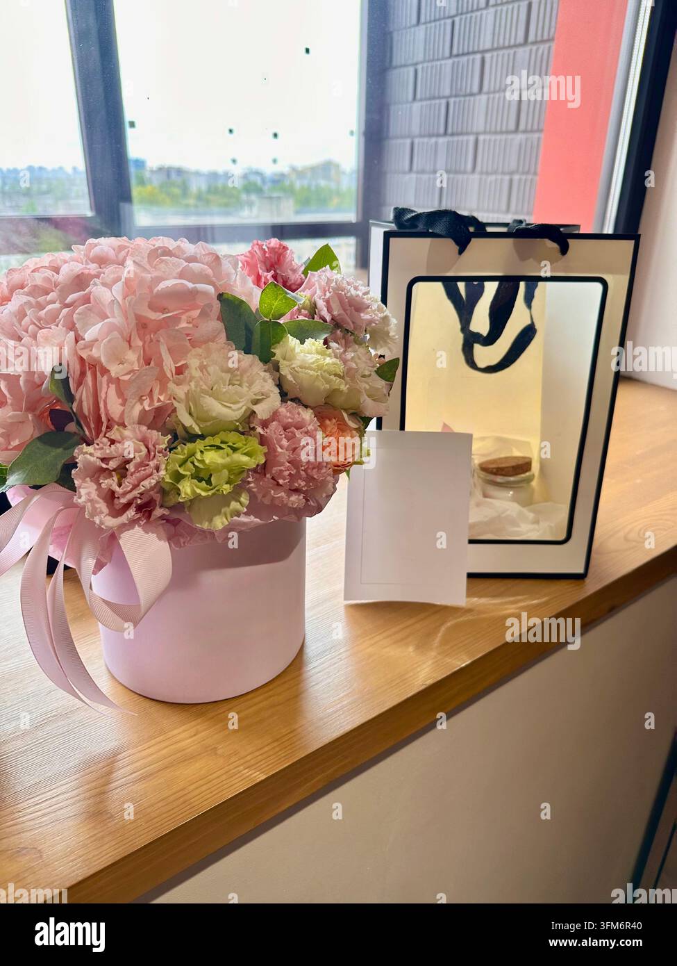 Composizione floreale rosa con biglietto vuoto e sacchetto regalo nella luce soffusa della giornata. - Immagine stock catturata con smartphone