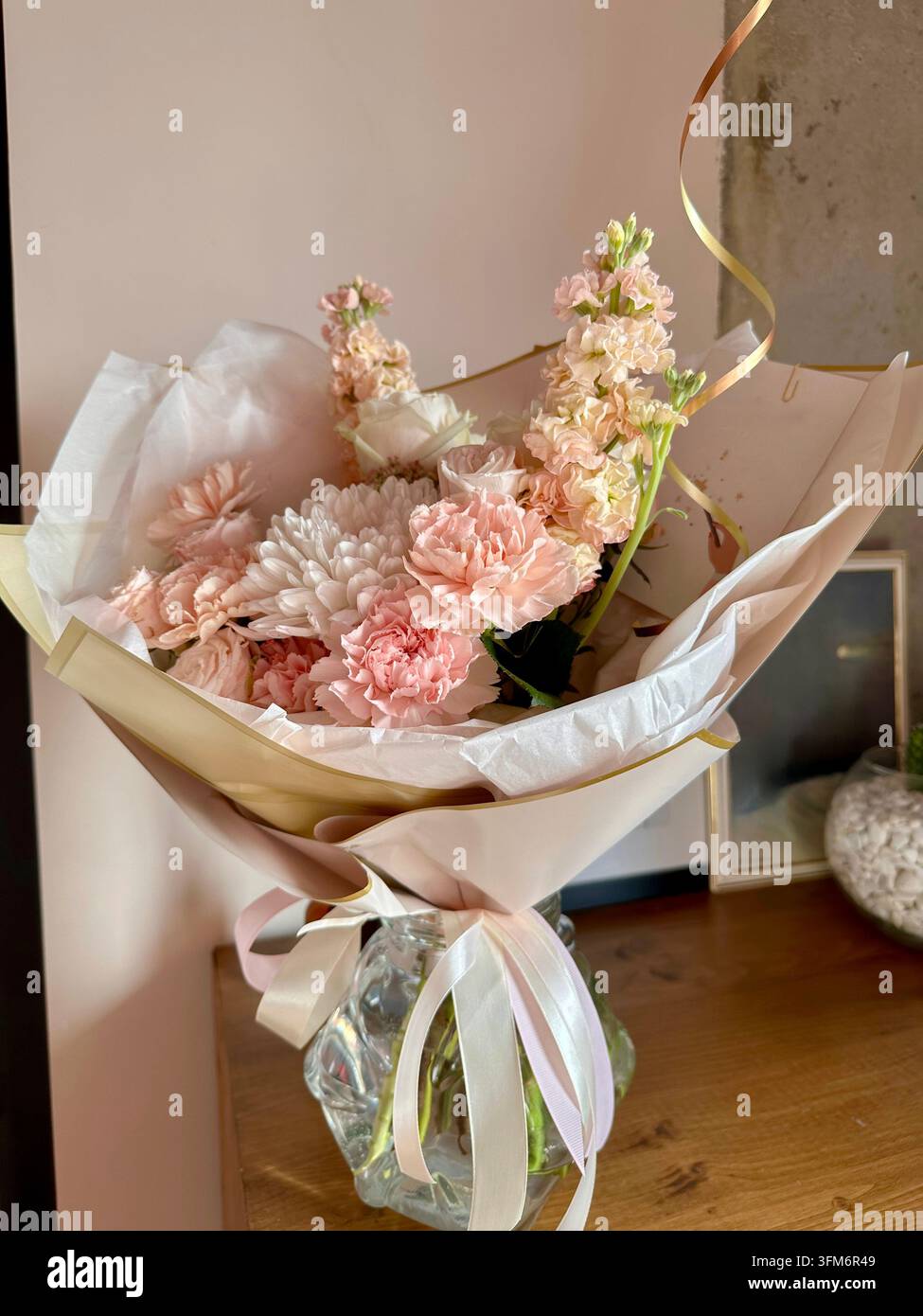 Mazzo di fiori pastello in vaso di vetro brilla sotto la calda luce del sole interna. - Immagine stock catturata con smartphone
