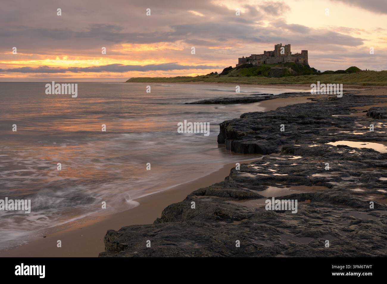 Il castello di Bamburgh nel Northumberland prima dell'alba, visto dalle Harkess Rocks Foto Stock