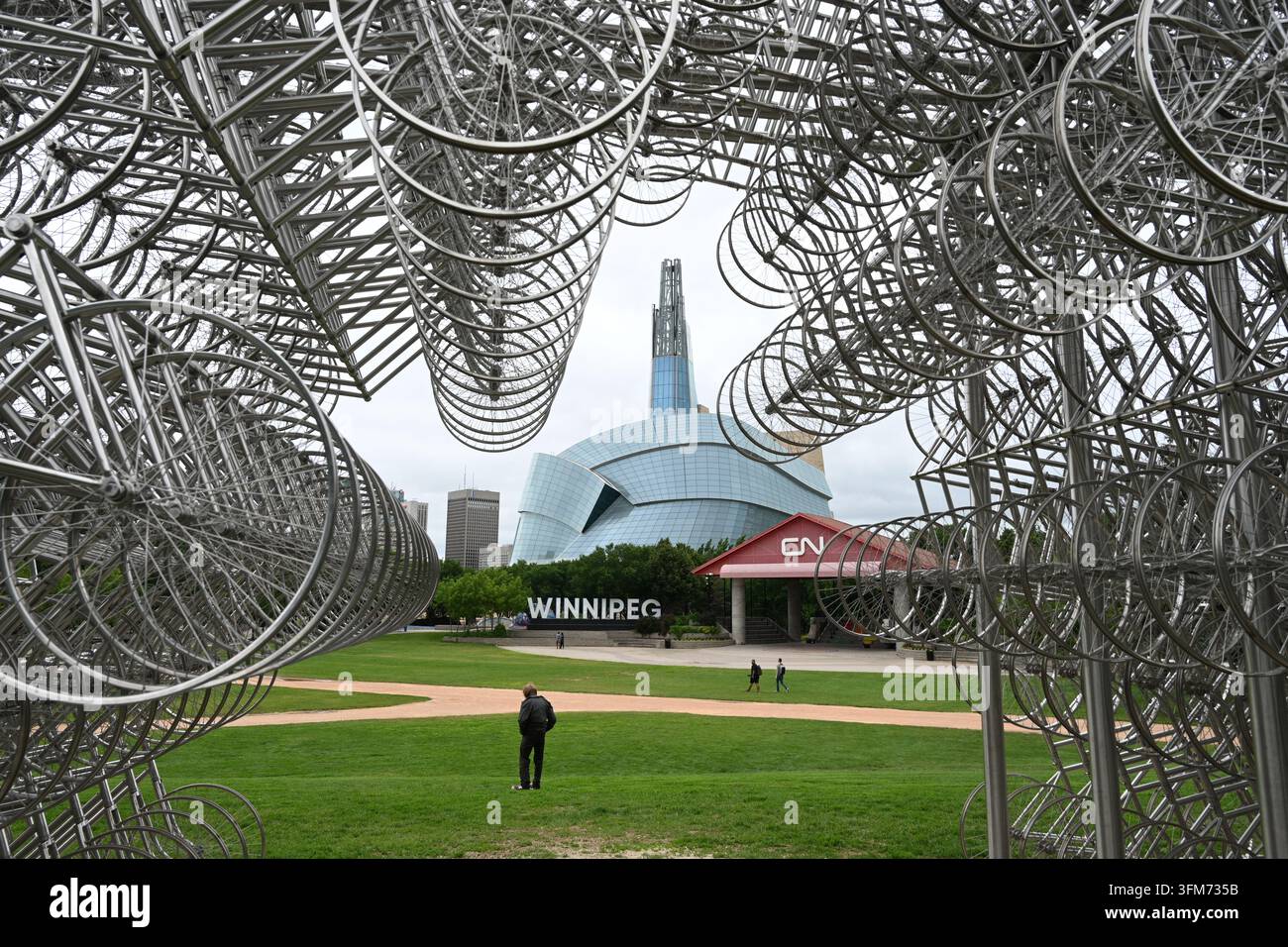 Winnipeg, Manitoba, Canada – 2 luglio 2026: Un uomo nel parco con il Museo canadese dei diritti umani sullo sfondo, Winnipeg, Manitoba. Foto Stock