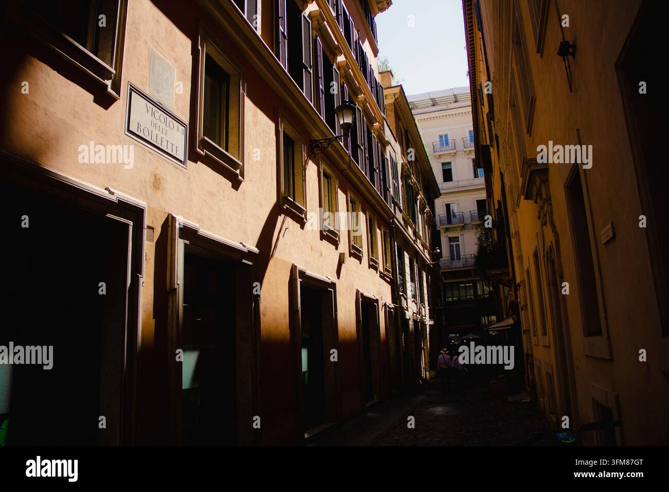 Strada stretta a Roma, Italia, con edifici storici e contrasto tra luce del sole e ombre Foto Stock