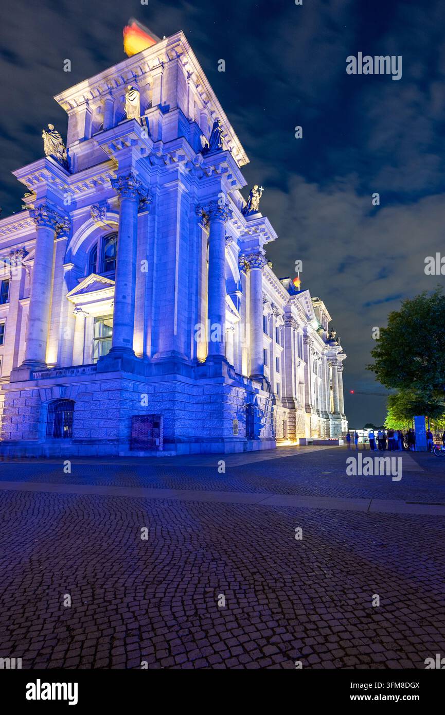 Illuminazione blu e accenti di luce calda definiscono una facciata classica ornata a Berlino di notte Foto Stock