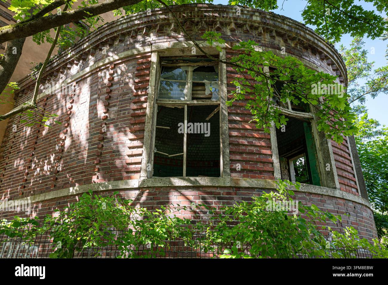 Edificio circolare in mattoni invaso dalla vegetazione con finestre rotte a Beelitz-Heilstätten nel Brandeburgo, Germania Foto Stock