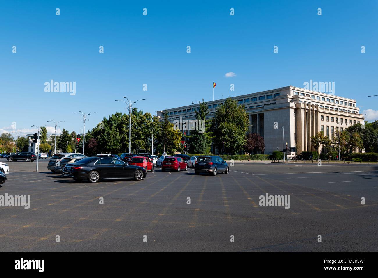 Bucarest, Romania - Sett 2026: La facciata architettonica del Palazzo Victoria, sede del governo, con auto che passano per la piazza. Foto Stock