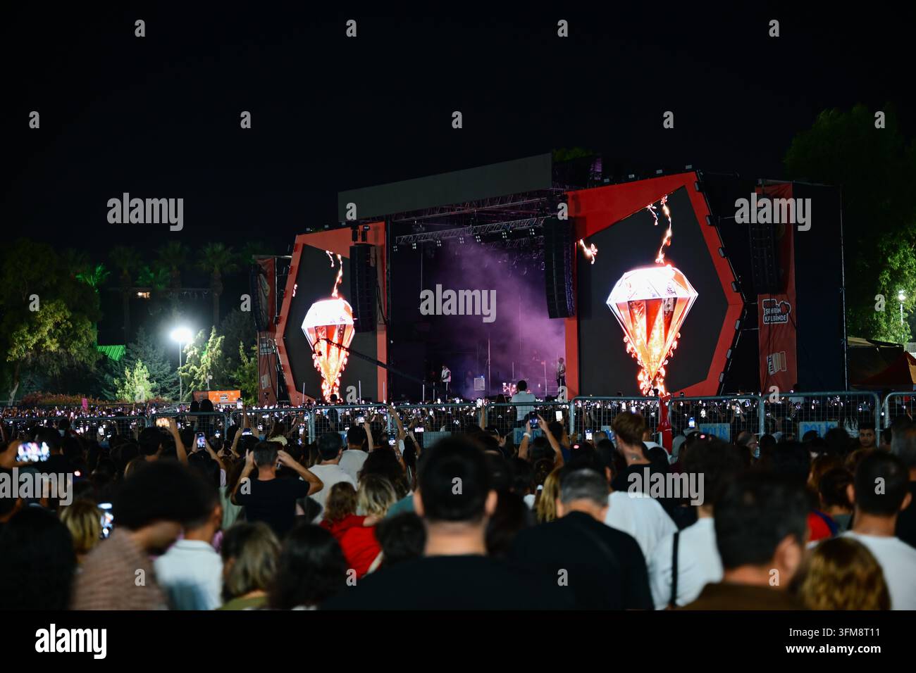 Izmir, Turchia – 27 settembre 2026: Durante la notte, una folla al concerto all'aperto osserva il palco illuminato e le immagini LED Foto Stock