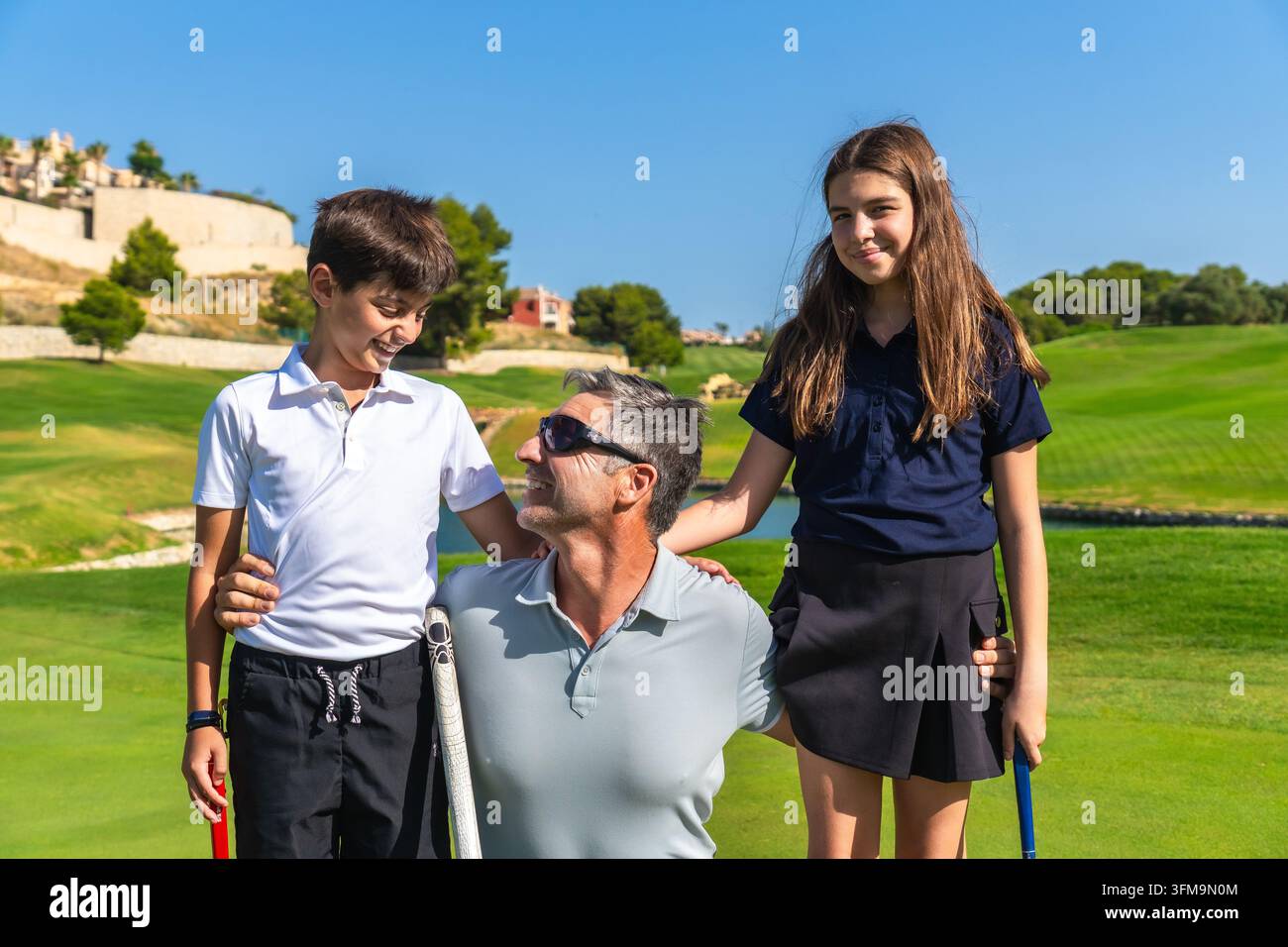 Padre che insegna golf ai bambini all'aperto sul campo Foto Stock