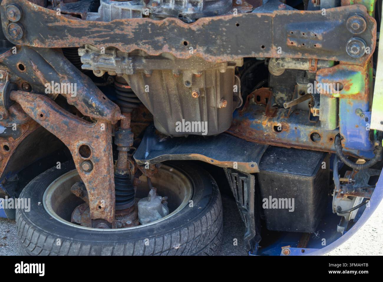 Pezzi di auto arrugginiti e componenti meccanici che mostrano decadimento e abbandono Foto Stock