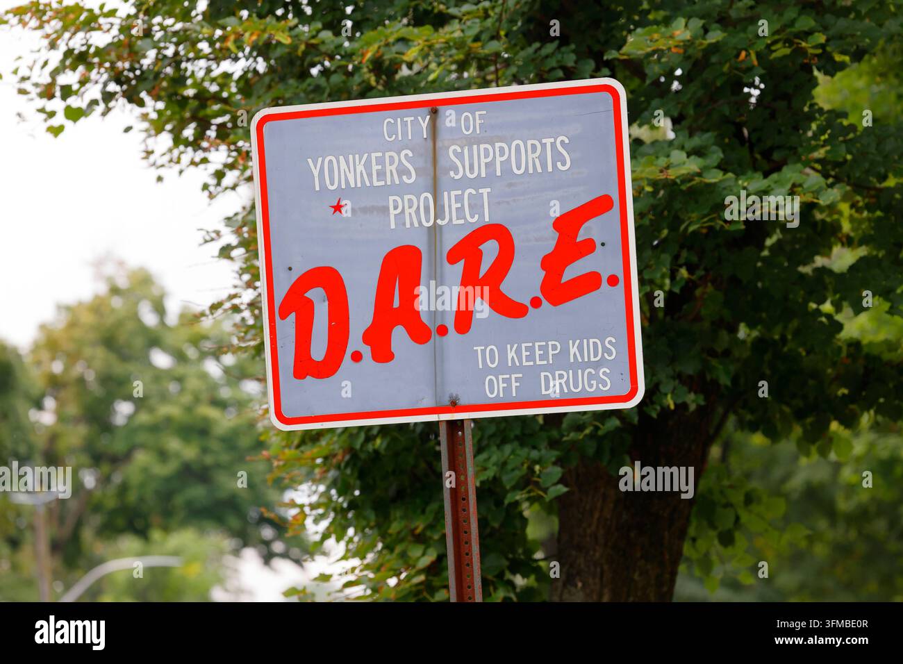 Un vecchio cartello stradale "City of Yonkers sostiene Project DARE.To Keep Kids Off Drugs" vicino a una scuola. Project DARE è Drug Abuse Resistance Education. Foto Stock