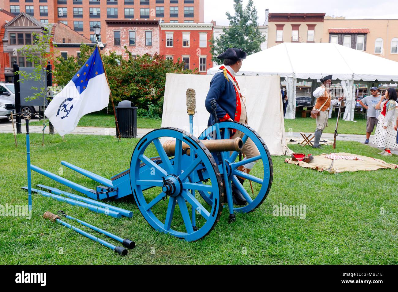 Un rievocatore della Guerra d'Indipendenza Americana in uniforme dell'Esercito Continentale si trova accanto a un cannone Grasshopper leggero da 3 libbre ... Foto Stock