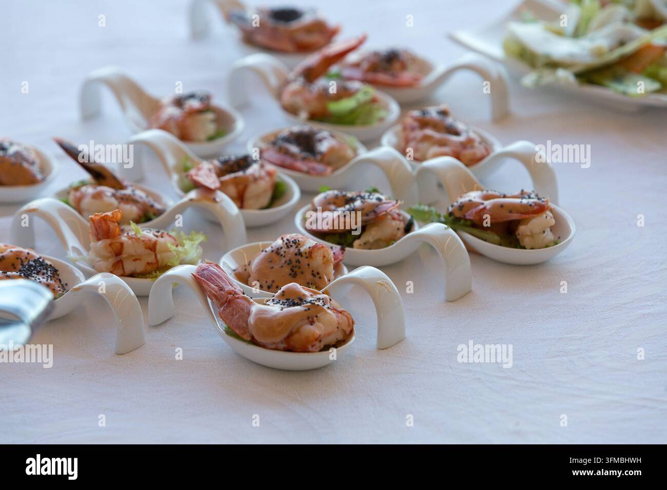 Antipasti individuali di gamberetti con salsa e semi di sesamo nero su eleganti cucchiai di ceramica Foto Stock
