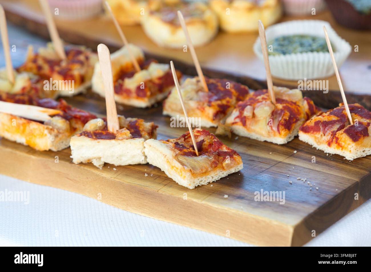 Mini pizze su una tavola di legno, pronte per essere gustate dagli ospiti come antipasti Foto Stock