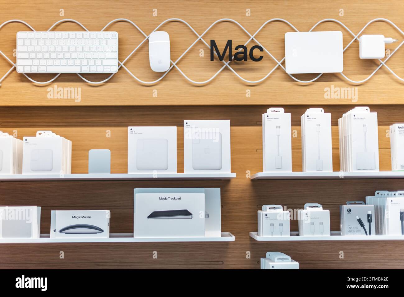 Bangkok, Thailandia, 4 maggio 2026: Computer Mac e accessori sono ordinatamente disposti su scaffali di legno con tastiere, mouse, trackpad, caricabatterie, Foto Stock