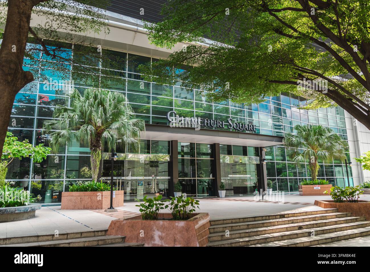 Bangkok, Thailandia, 3 maggio 2026: L’ingresso di Chamchuri Square presenta una facciata in vetro, una sistemazione a palme, ampi gradini e alberi frondosi a Bangkok. Foto Stock