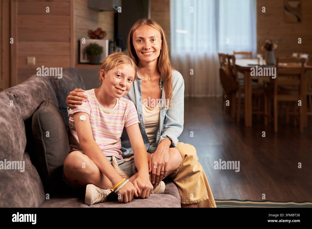Ritratto di madre e bambina con monitor della glicemia a casa Foto Stock