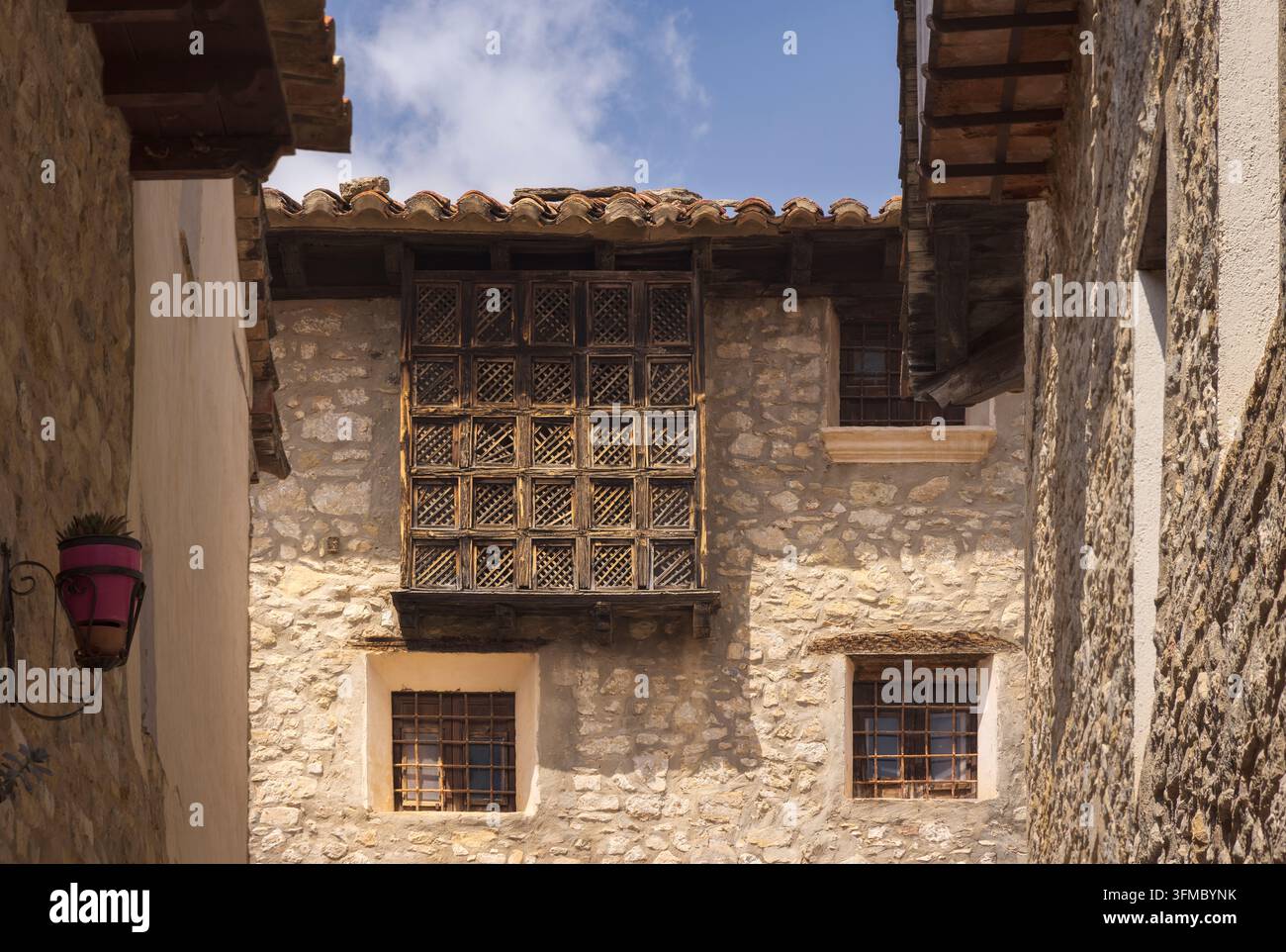 Una vista affascinante degli edifici in pietra di Mirambel rivela disegni di finestre intricati in mezzo a un cielo blu terso, Teruel, Spagna Foto Stock