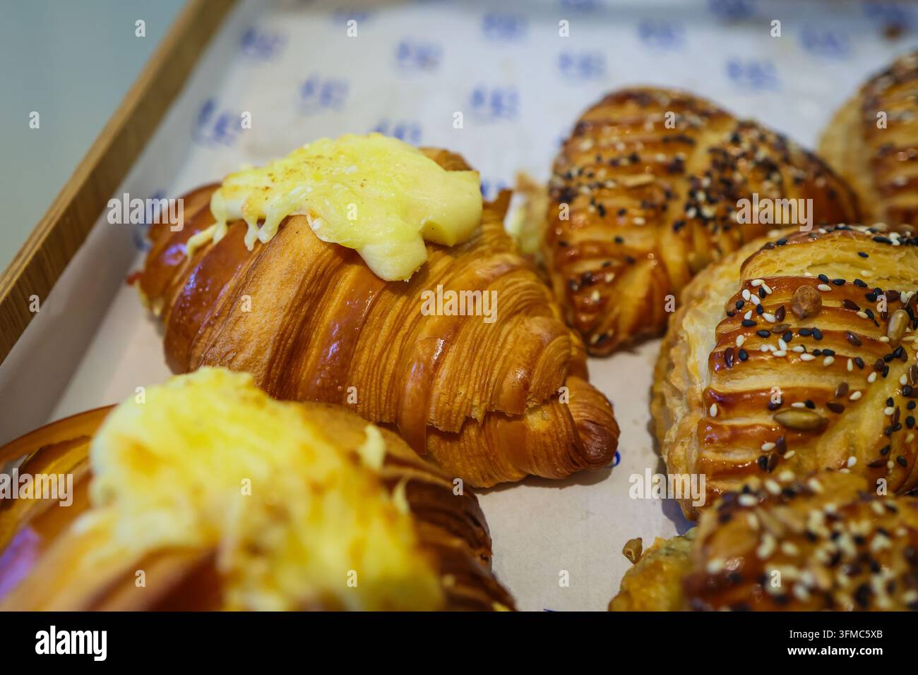 Assortimento di pasticcini appena sfornati in stile francese, tra cui croissant dorati al burro con condimenti cremosi e pasticcini salati laminati decorati con Foto Stock