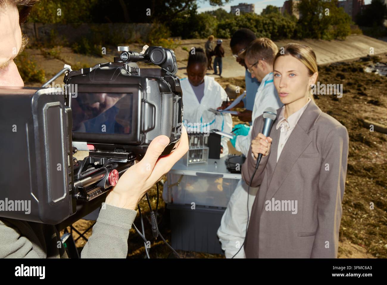 Giornalista donna che riferisce sulla ricerca ambientale all'aperto Foto Stock