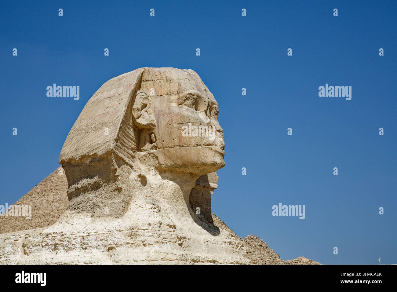 GIZA, EGITTO – 9 MARZO 2026: Profilo della testa della Grande Sfinge di Giza contro un cielo blu profondo, con la Piramide di Chefren sullo sfondo. Datato da t Foto Stock