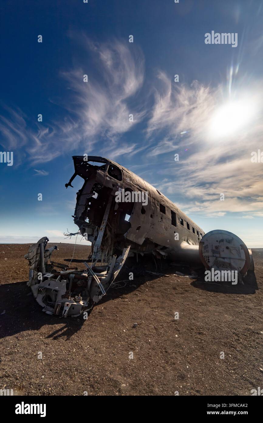 Relitto di aereo arrugginito abbandonato si trova su una pianura desertica desolata sotto un drammatico cielo blu con sottili nuvole bianche. Foto Stock