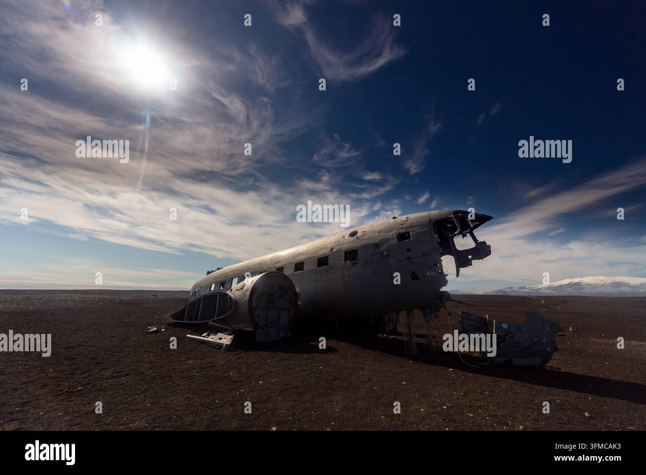 Relitto di aereo arrugginito abbandonato si trova su una pianura desertica desolata sotto un drammatico cielo blu con sottili nuvole bianche. Foto Stock