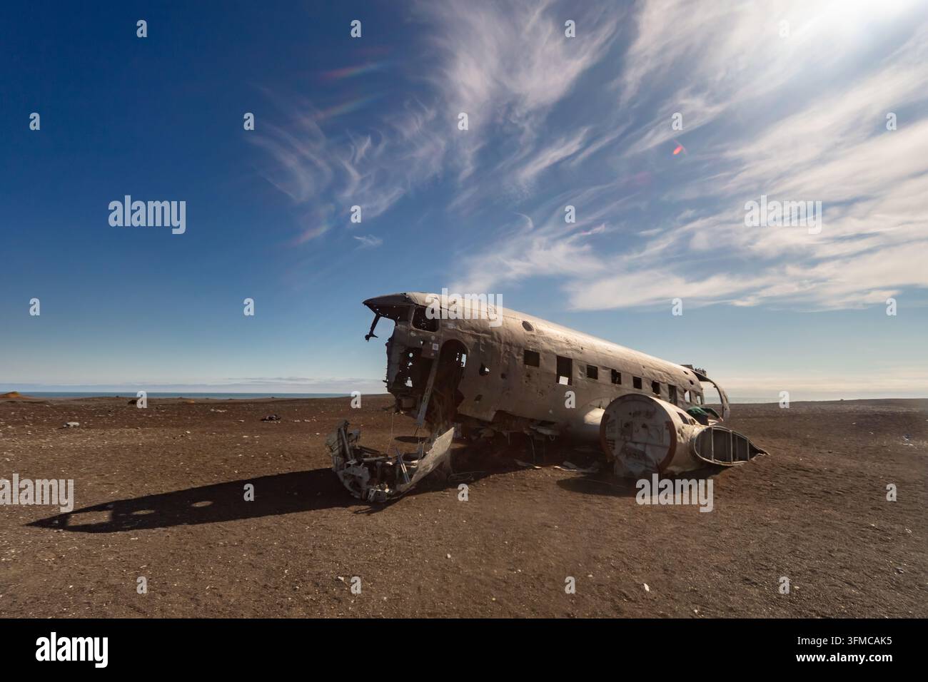 Relitto di aereo arrugginito abbandonato si trova su una pianura desertica desolata sotto un drammatico cielo blu con sottili nuvole bianche. Foto Stock