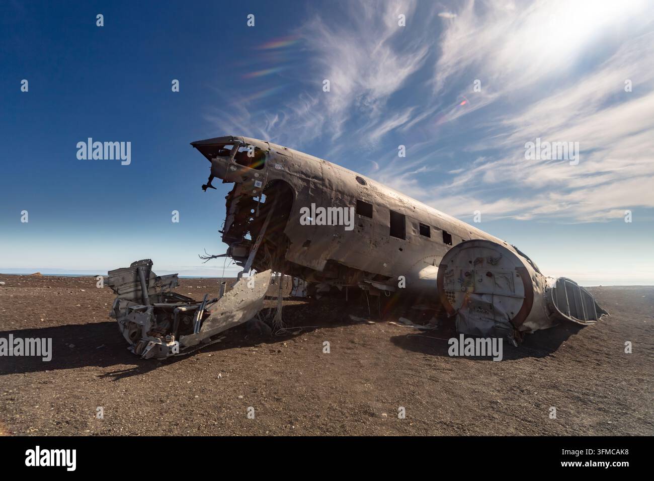 Relitto di aereo arrugginito abbandonato si trova su una pianura desertica desolata sotto un drammatico cielo blu con sottili nuvole bianche. Foto Stock