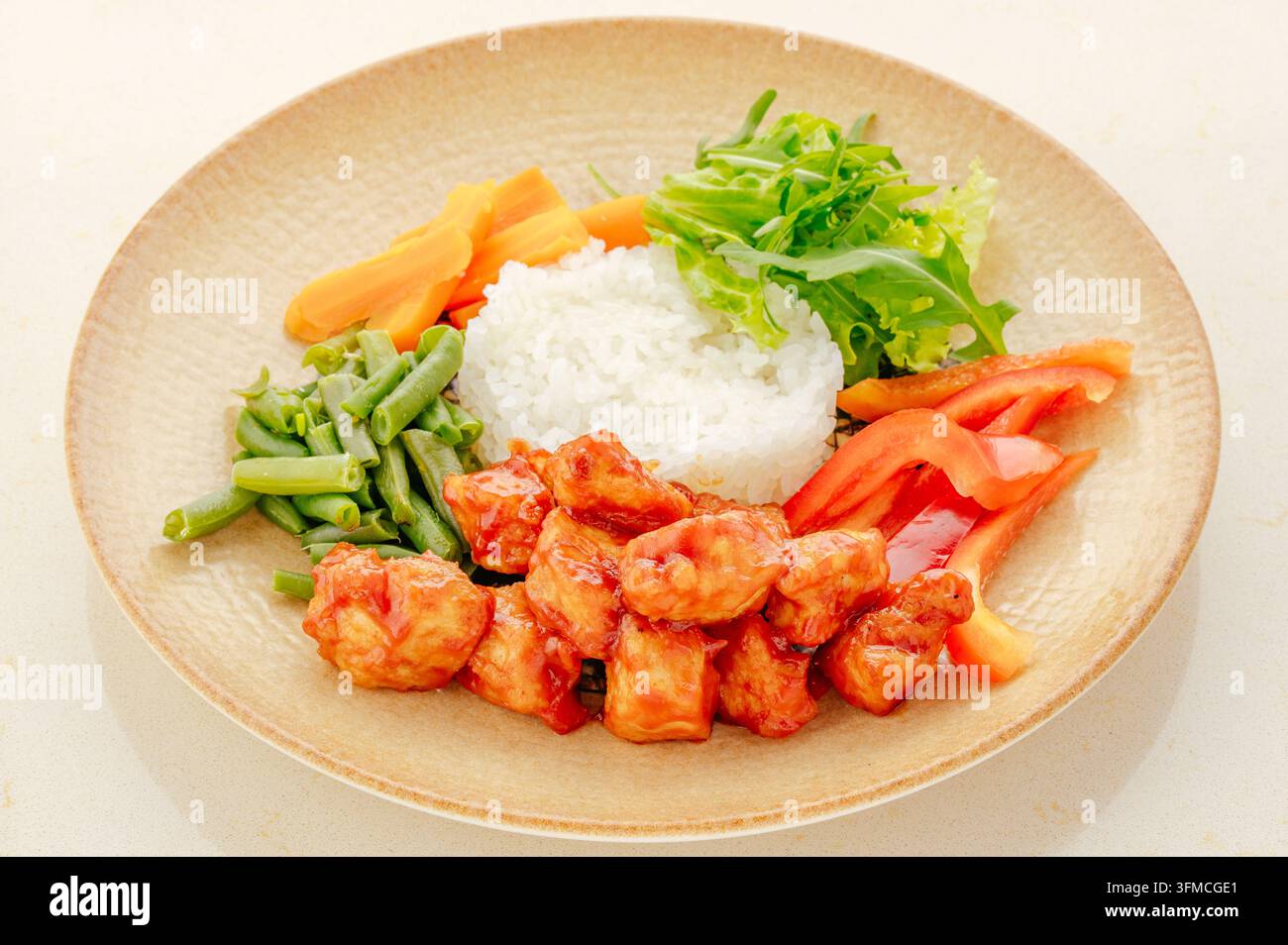 Pollo dolce e aspro con riso e verdure fresche su un piatto Foto Stock