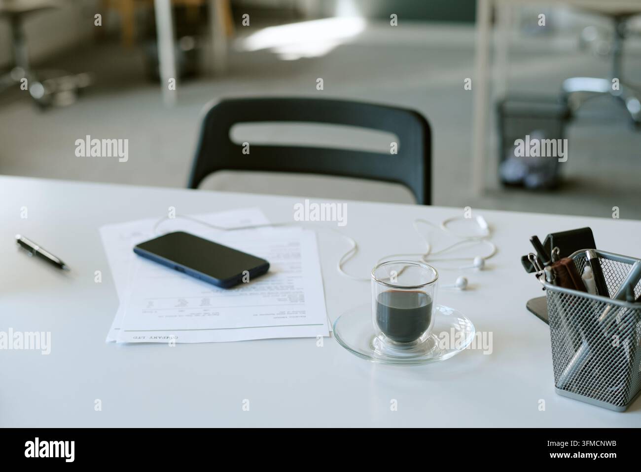 Bicchiere di caffè con smartphone e documenti sulla scrivania Foto Stock