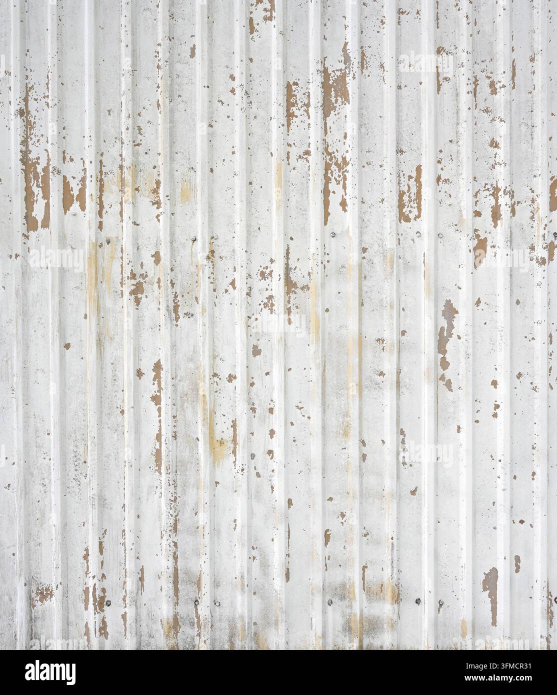 Rivestimento in metallo galvanizzato ondulato dipinto di bianco sporco con creste verticali e accumulo di sporcizia concentrato vicino al fondo Foto Stock