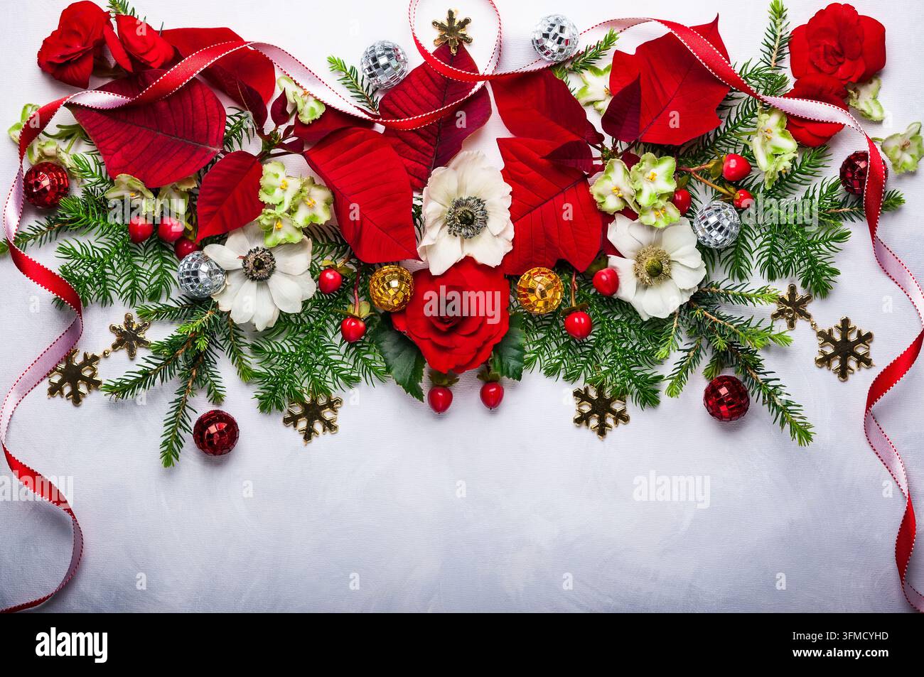 Decorazione natalizia con poinsettia, agrifoglio, edera, vischio e rami di abete su sfondo chiaro Foto Stock