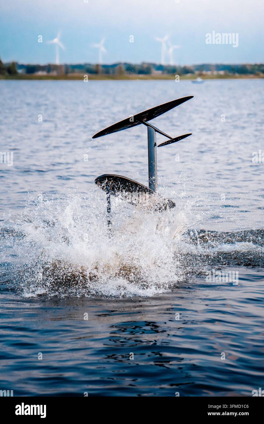 Tavola da surf ad idrofoil capovolta con le ali fuori dall'acqua che crea un grande schizzo. Foto Stock