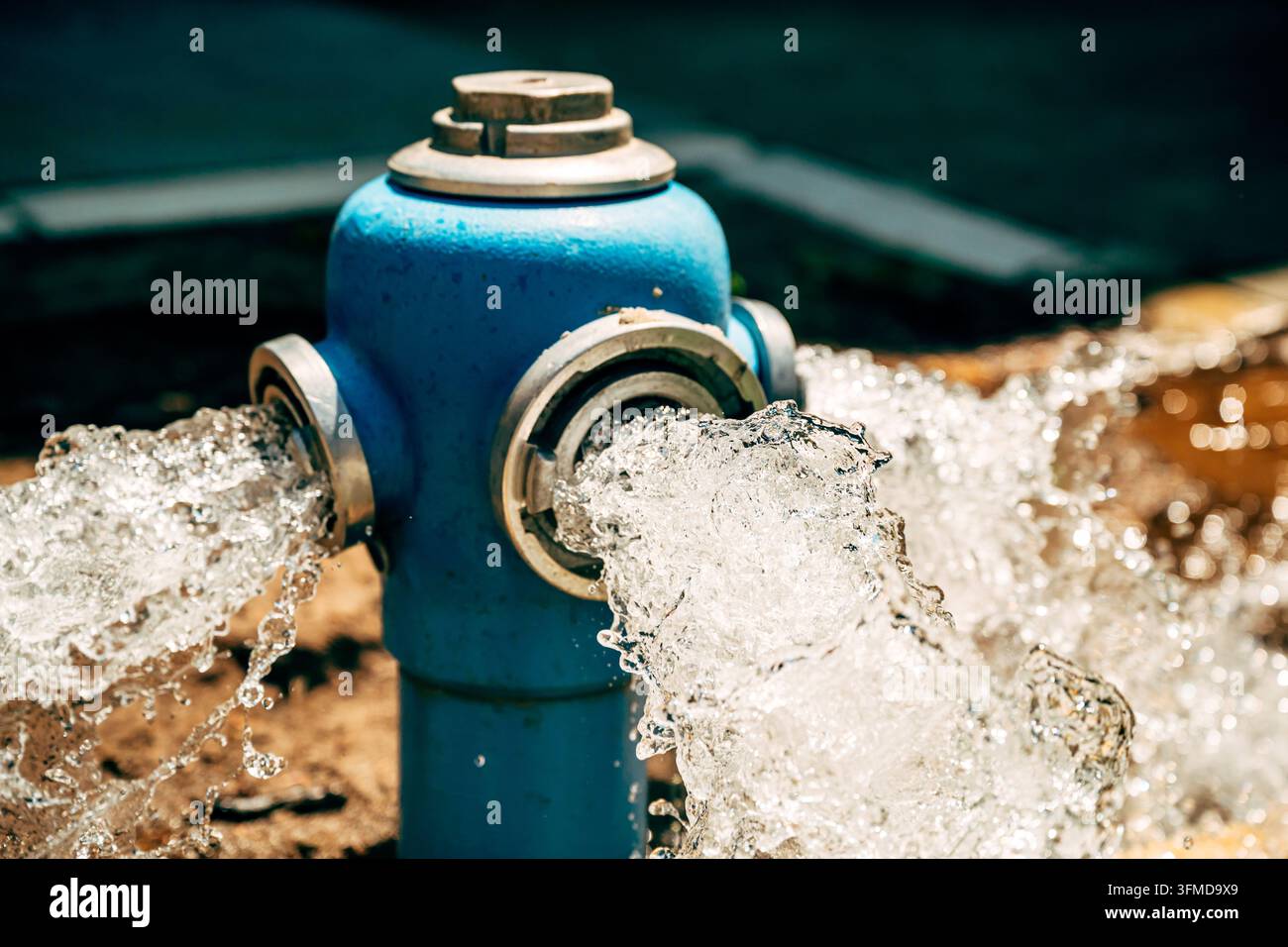 Idrante blu che rilascia un potente getto d'acqua durante lo sciabordio del sistema. Infrastruttura urbana, distribuzione dell'acqua e operazione di manutenzione tematiche Foto Stock