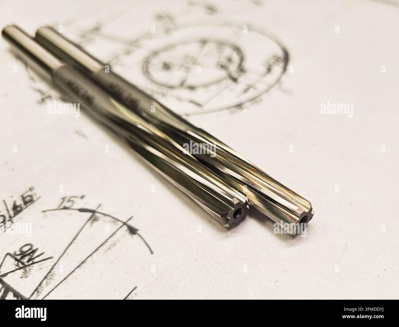 Due alesatori metallici per la finitura di fori di precisione, mostrati in primo piano su un disegno tecnico. Foto Stock