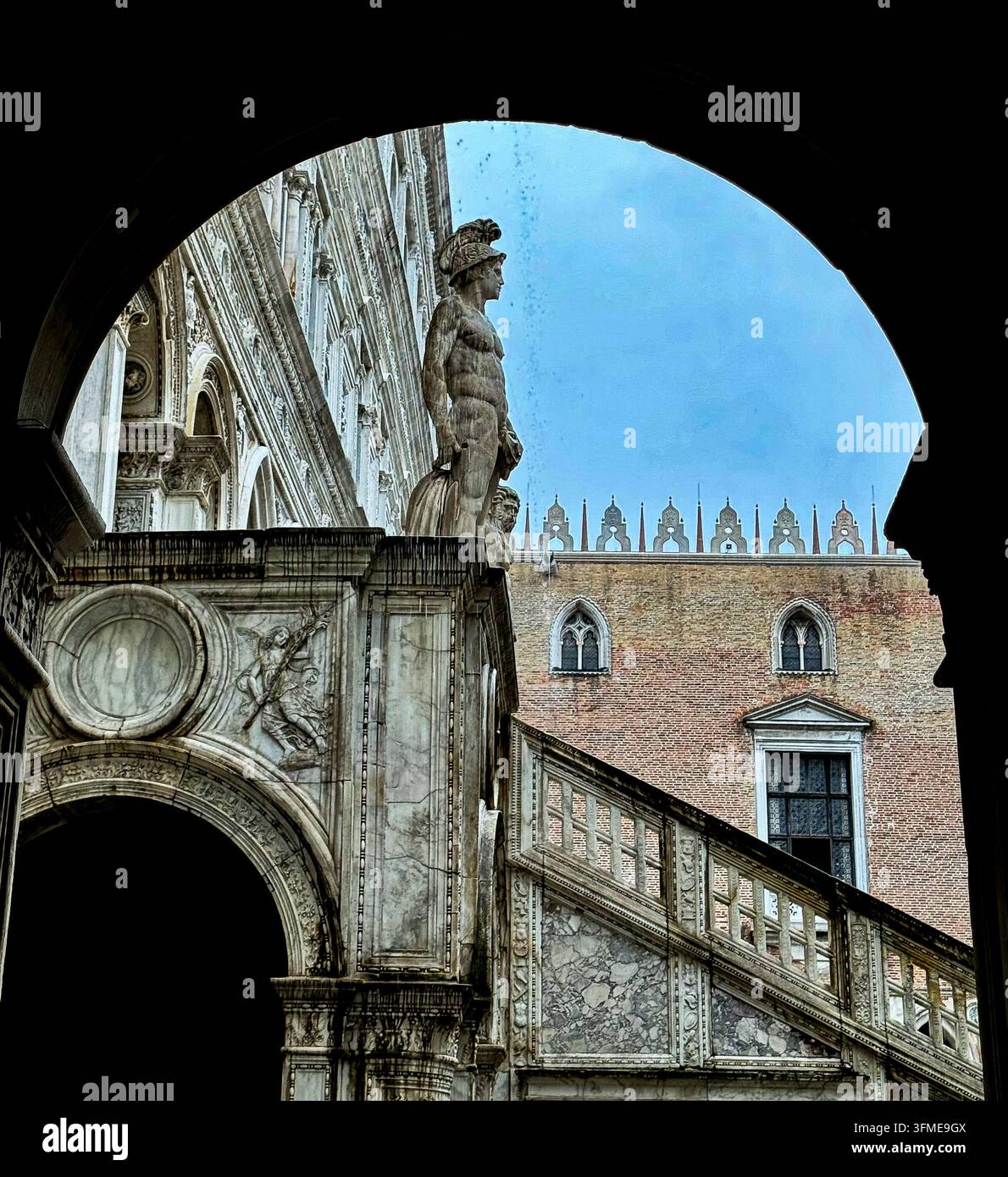 Una statua si erge su un piedistallo come parte di un edificio storico. La veduta cattura scale e dettagli architettonici sotto un cielo nuvoloso. L'ambientazione mostra - Immagine stock catturata con smartphone