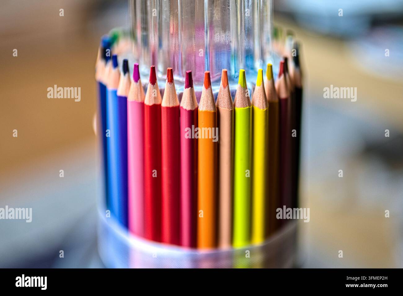 Primo piano di matite colorate in piedi in un cilindro con sfondo sfocato, materiale artistico e scolastico per il disegno. Foto Stock