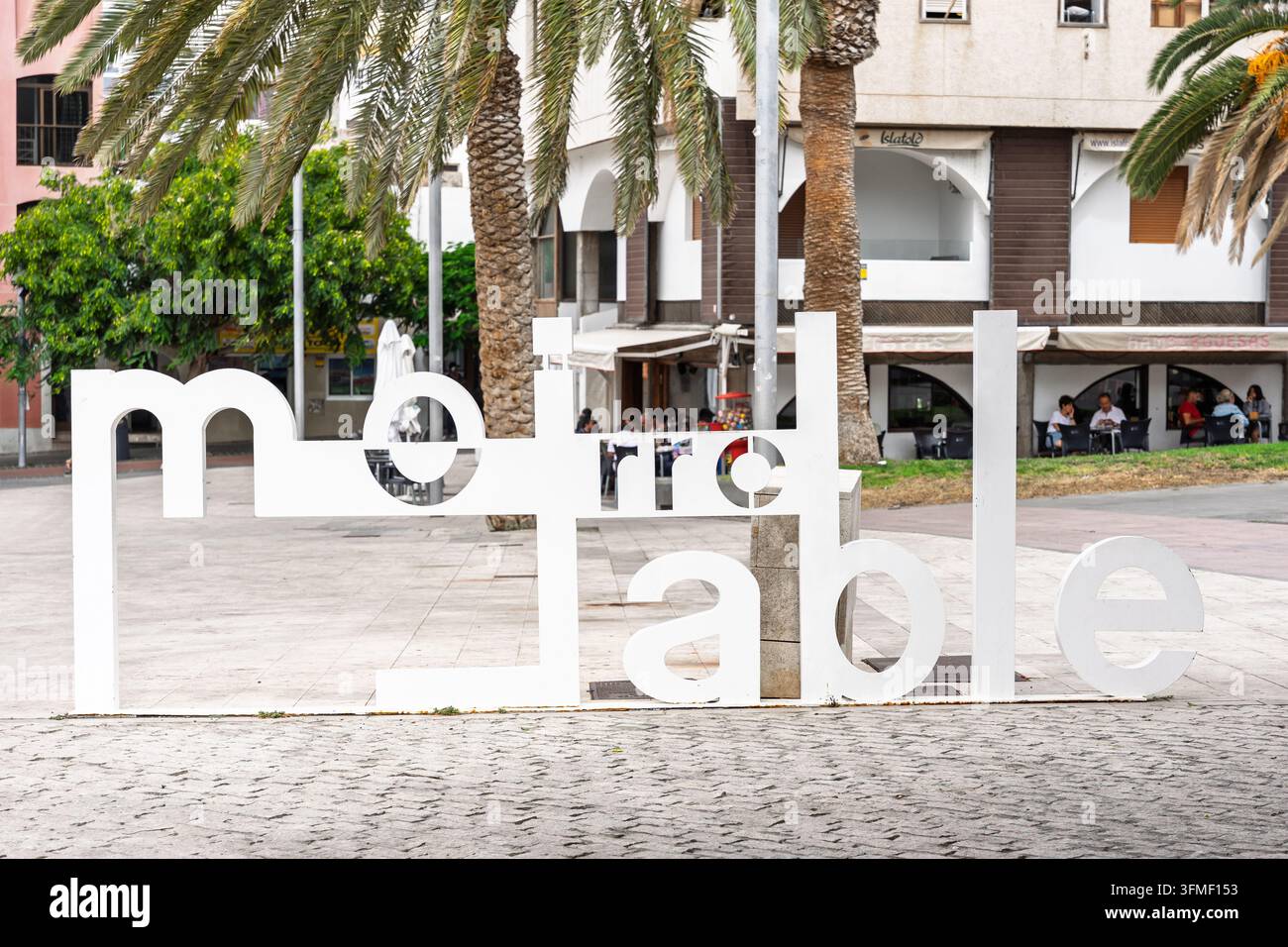 Grande scultura tipografica "Morro Jable" in una piazza pubblica con palme, aree sedute e edifici circostanti. Foto Stock