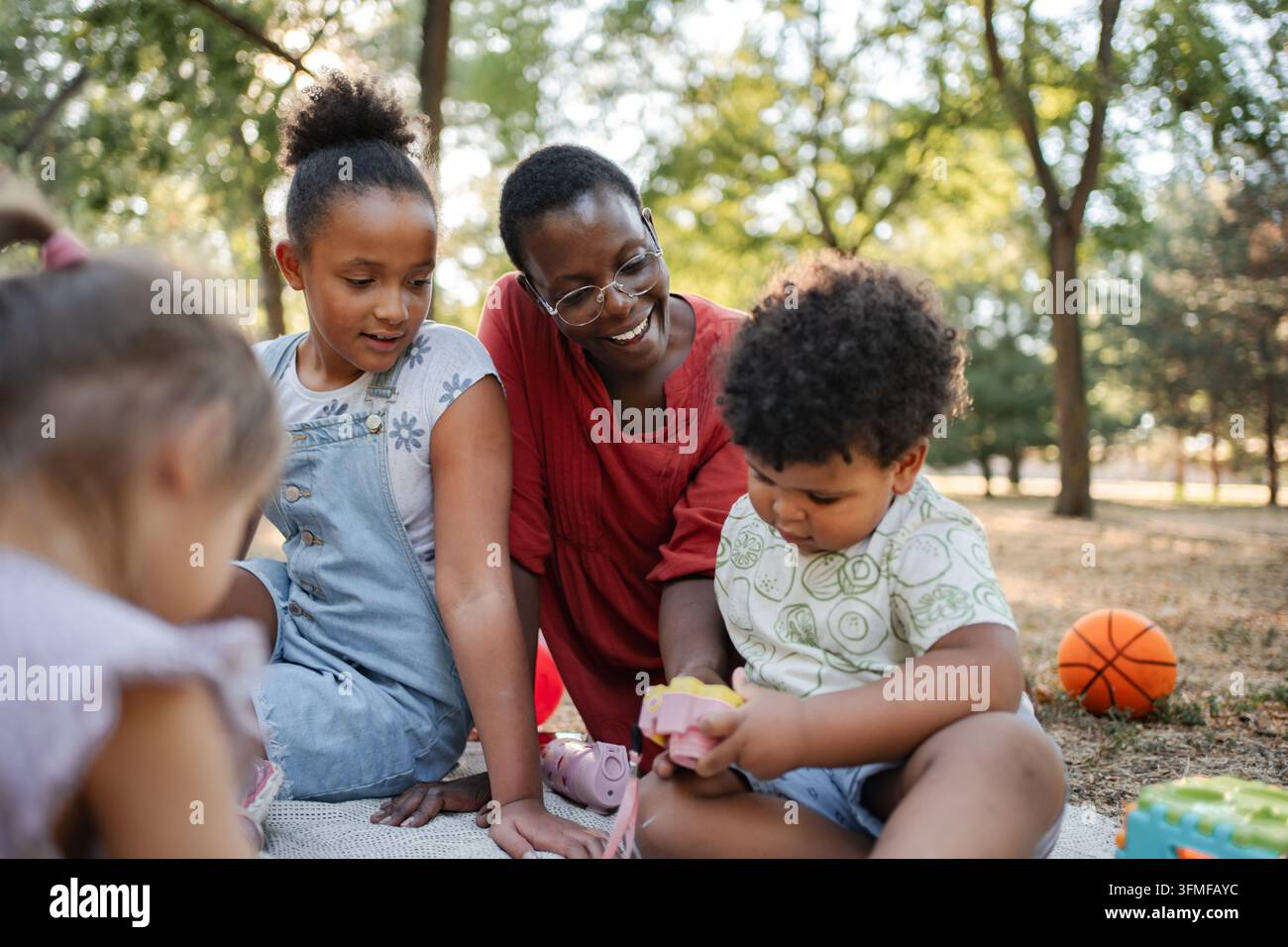 Bambinaia che gioca con i bambini nel parco durante una giornata di sole Foto Stock