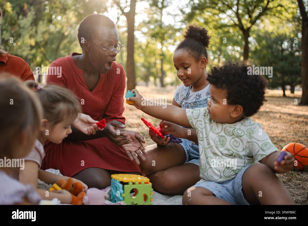 Insegnante di scuola materna che gioca con i bambini nel parco Foto Stock