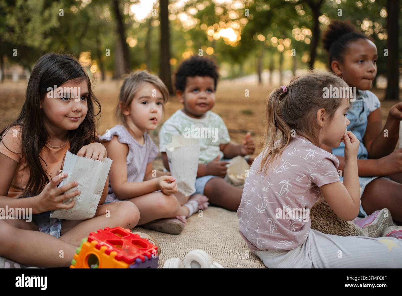 I bambini guardano un film nel parco e mangiano popcorn Foto Stock
