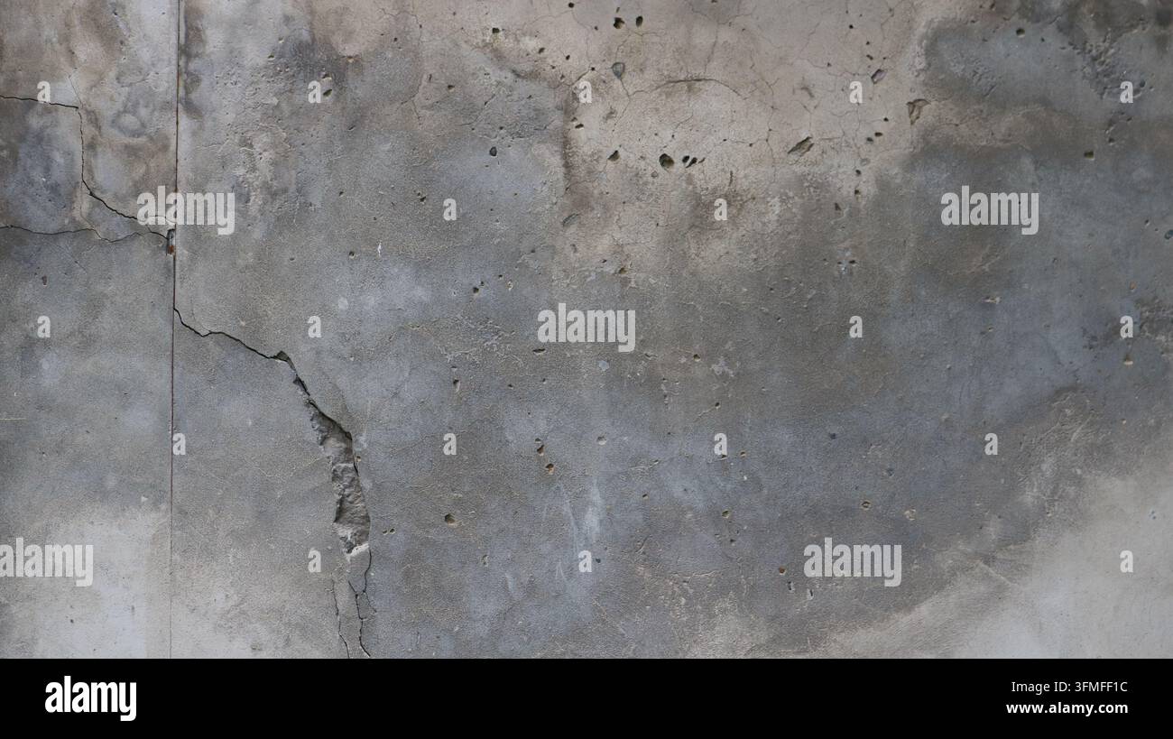 Textura di vecchio cemento grigio con crepe profonde e buche. Uno sfondo grunge cupo con una struttura di cemento poroso, tracce di erosione e umidità Foto Stock