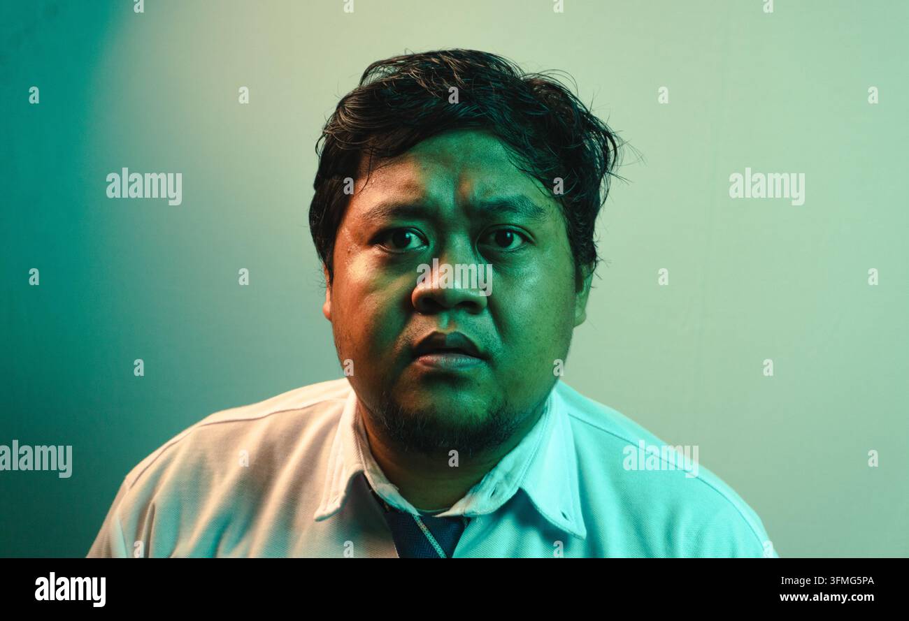 Un ritratto macro ad altissima definizione mette in risalto il volto di un uomo indonesiano adulto che fissa intensamente lo spettatore. L'uomo mostra un'espressione severa, sli Foto Stock