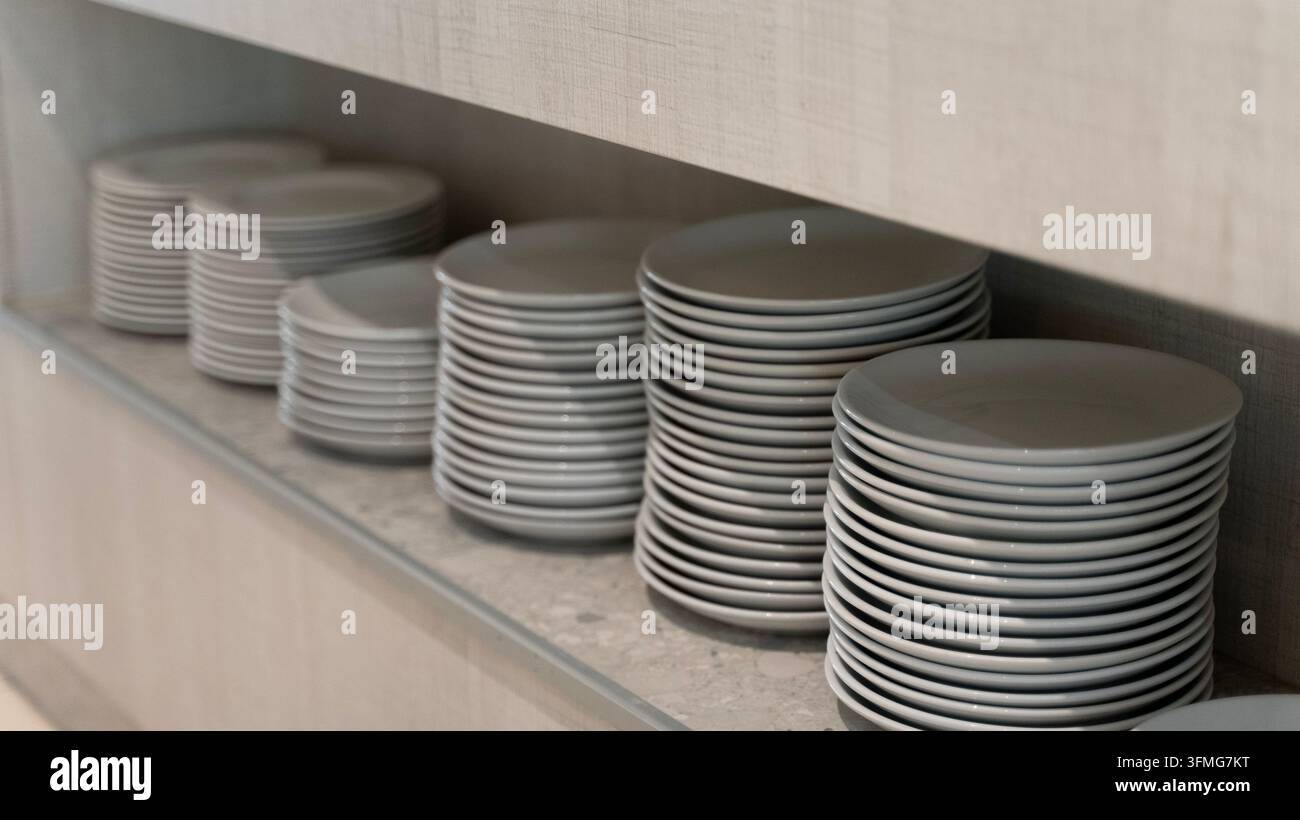 Piatti di ceramica bianca impilati su uno scaffale nella cucina del ristorante Foto Stock