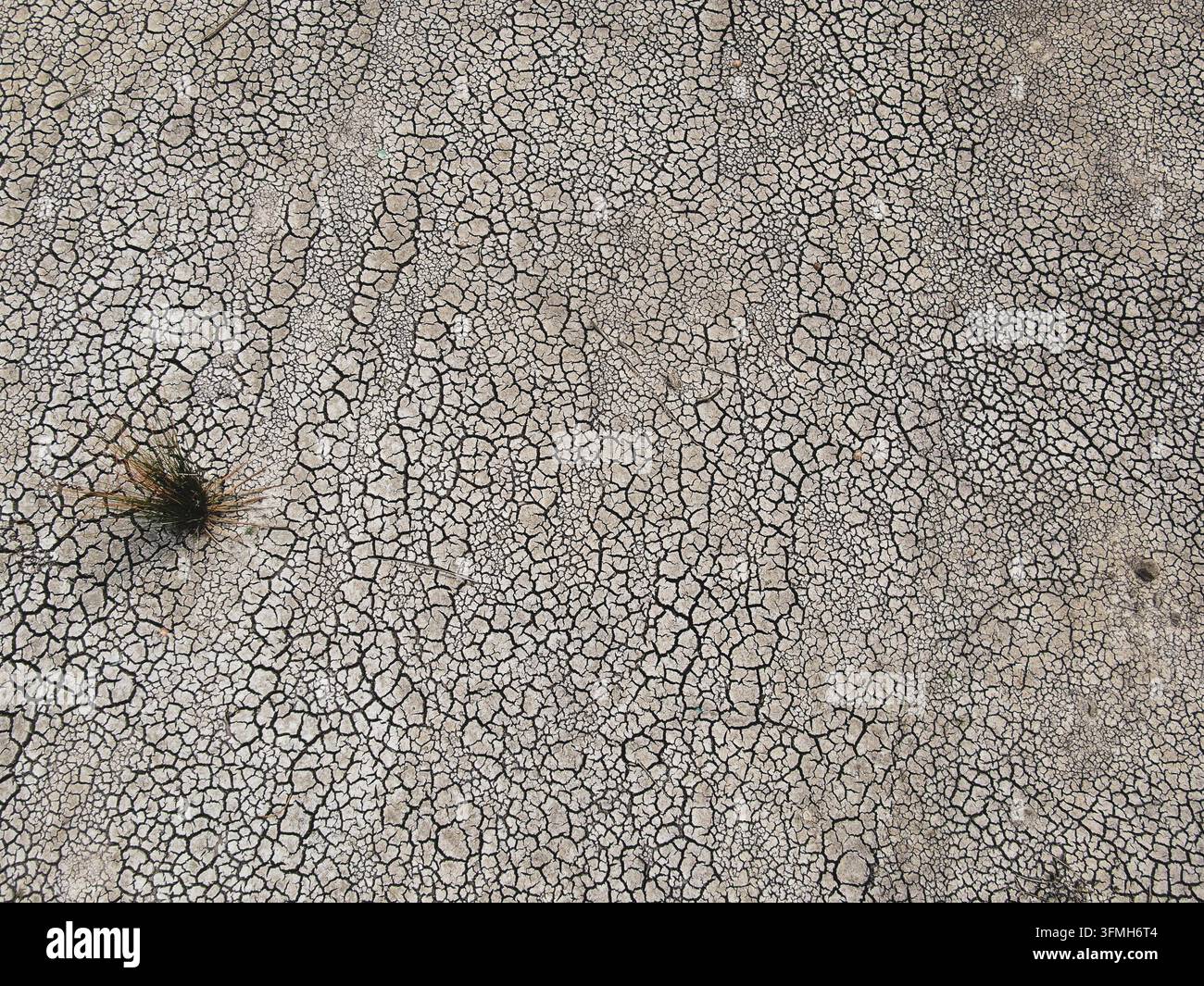 Vista aerea di terra arida divisa in un mosaico di lastre di argilla arricciate e cotte dal sole, una testimonianza netta di una prolungata siccità e della scomparsa dell'acqua. Foto Stock