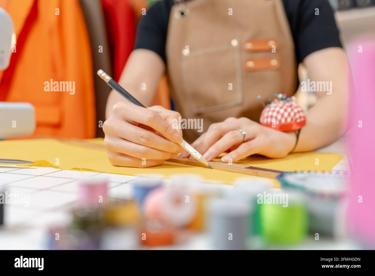 Designer di moda professionista che lavora in un moderno atelier di cucito, misurando, segnando e tagliando modelli di stoffa per la produzione di abbigliamento su misura. Creati Foto Stock