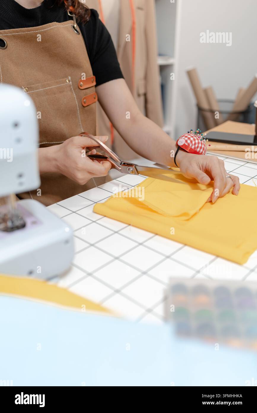 Designer di moda professionista che lavora in un moderno atelier di cucito, misurando, segnando e tagliando modelli di stoffa per la produzione di abbigliamento su misura. Creati Foto Stock