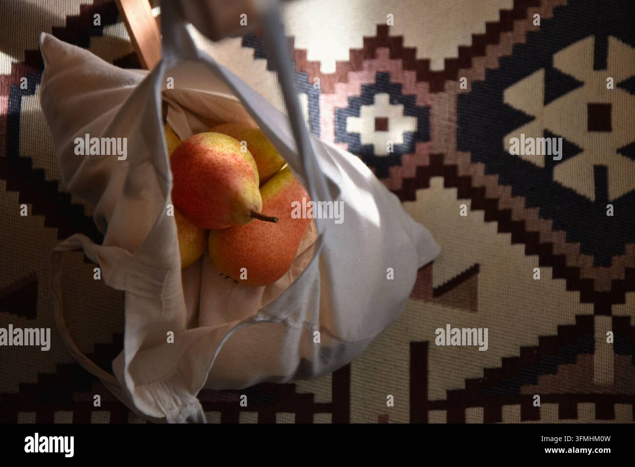 Pere freschi in una borsa di tela appesa sopra il tappeto con motivo kilim tradizionale Foto Stock