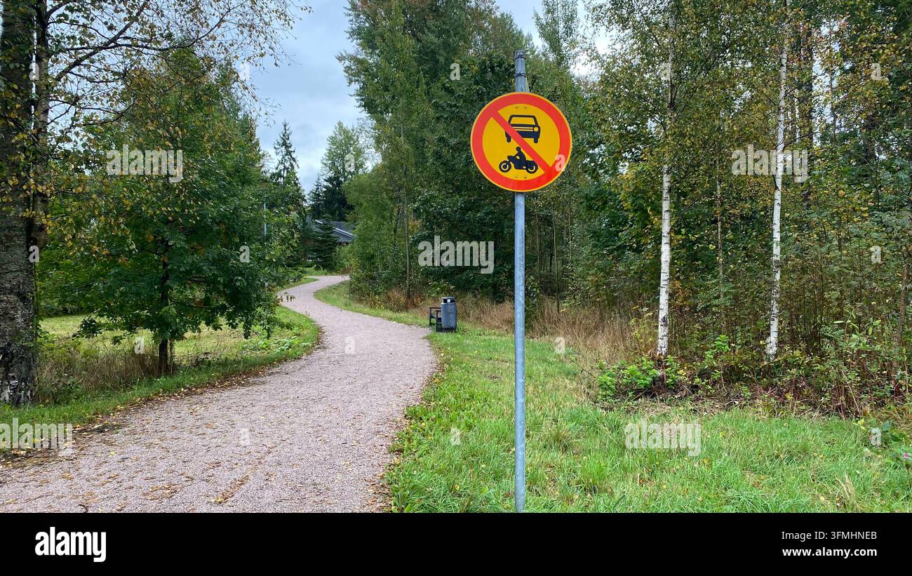 Segnale stradale che vieta veicoli a motore o motociclette su un percorso pedonale in un parco verde Foto Stock