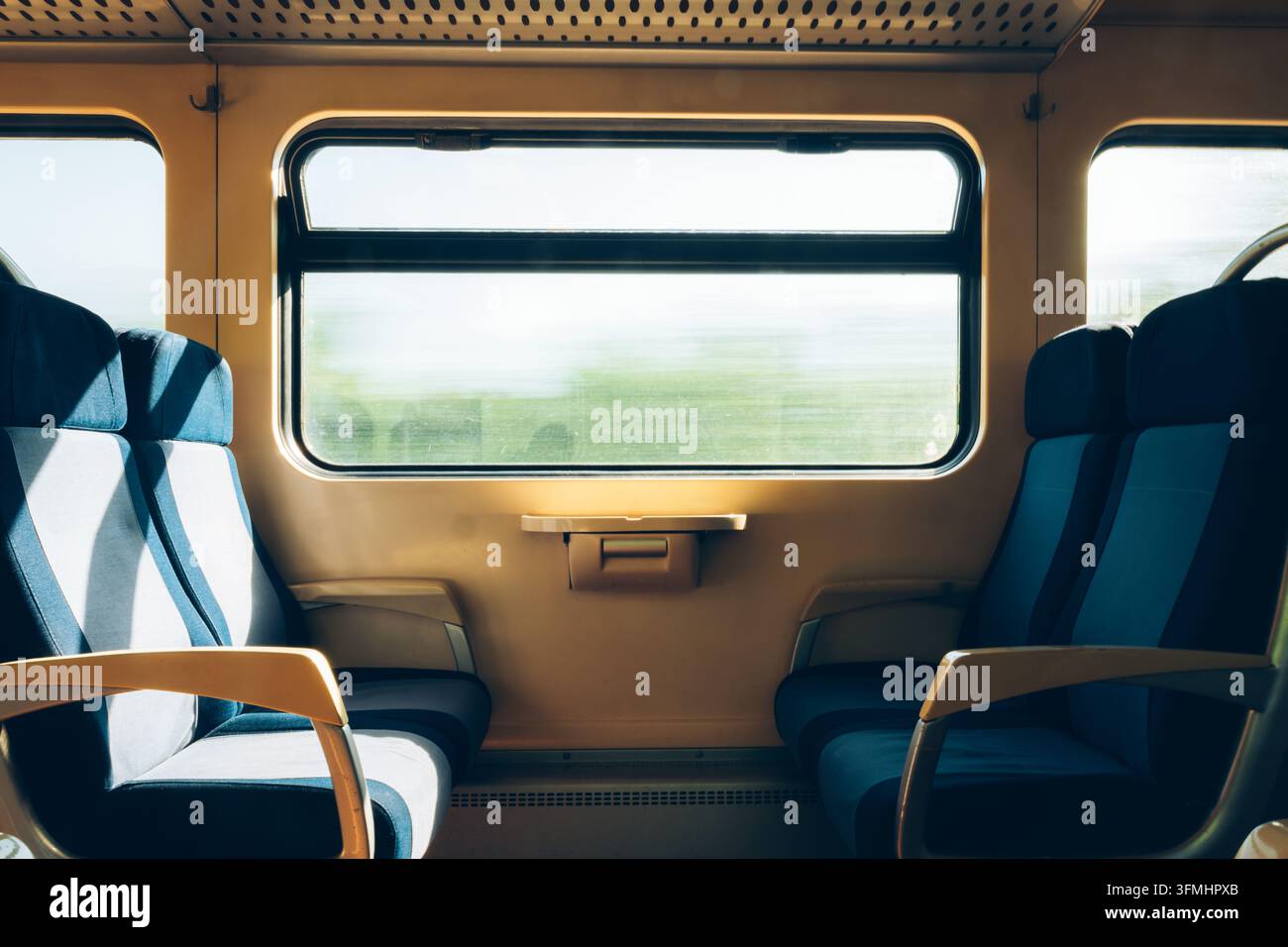 Posti vuoti uno di fronte all'altro in un tranquillo vagone del treno. Concetto di trasporto pubblico, viaggio dei passeggeri, pendolarismo sereno e logistica ferroviaria Foto Stock