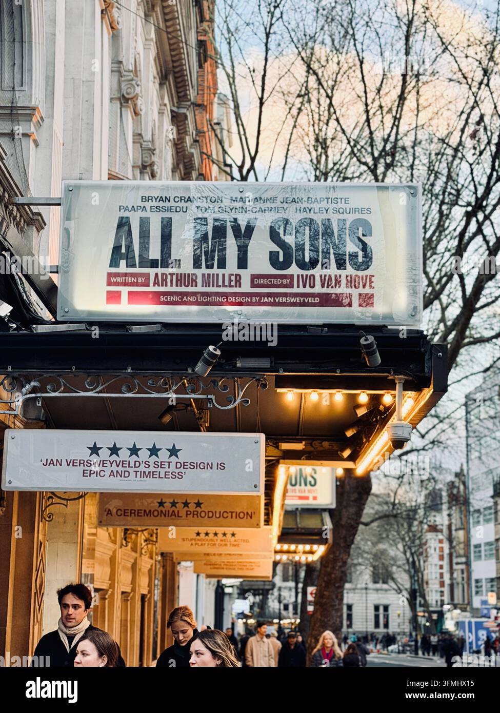 Londra, Regno Unito – Veduta stradale di una facciata di teatro con un grande cartellone pubblicitario per "Tutti i miei figli" di Arthur Miller e pedoni an - Immagine stock catturata con smartphone