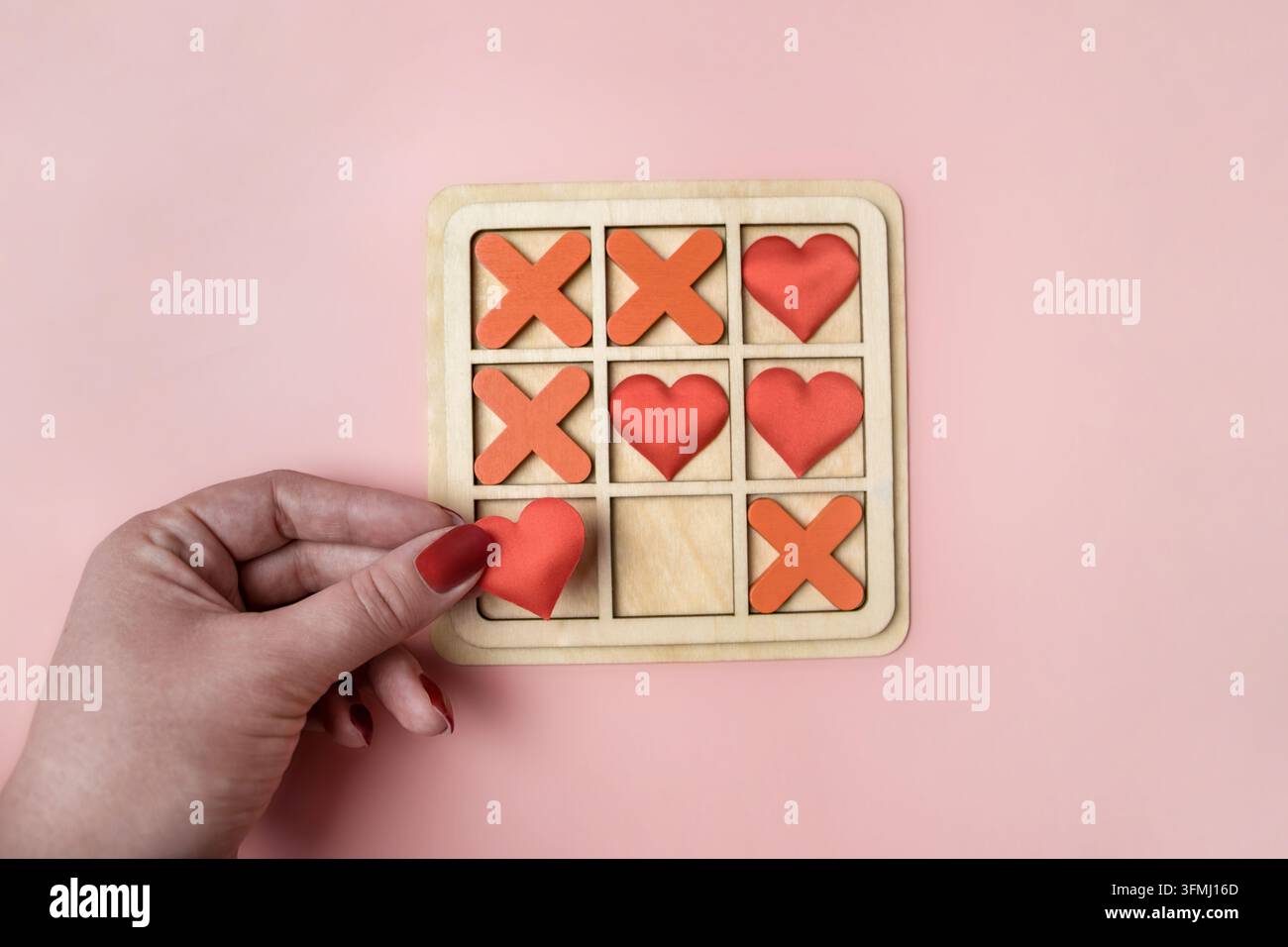 Una donna che gioca a tic tac toe in legno con cuori. Vista dall'alto. Foto Stock